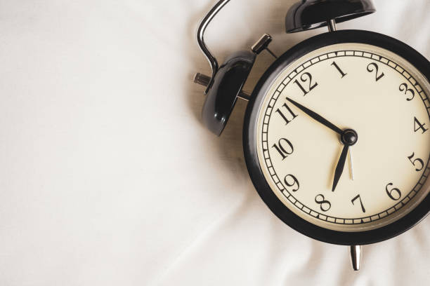 cierre el reloj despertador vintage negro en el espectáculo de tela blanca antes de las ocho, reloj en la mañana con espacio de copia - 8 oclock fotografías e imágenes de stock