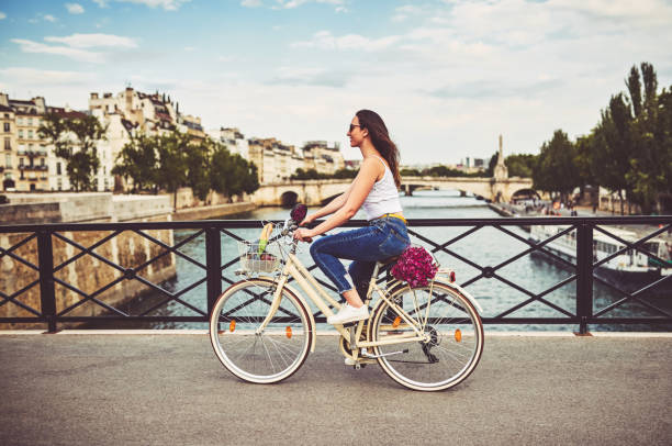 Peddling through the city of Paris Shot of a young woman touring the city of Paris with a bicycle riding photos stock pictures, royalty-free photos & images