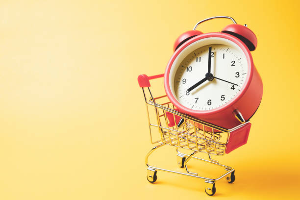 tiempo de compra, carrito de compras con reloj despertador vintage rojo mostrar 8 o'clock sobre fondo amarillo - 8 oclock fotografías e imágenes de stock