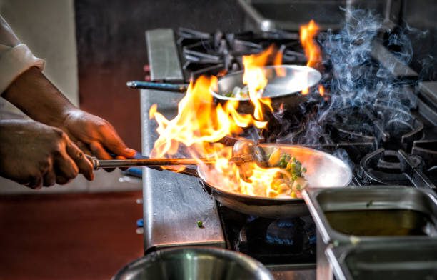 Flambe flame food frying pan Preparing Indian food by Flame in frying pan kitchen on fire stock pictures, royalty-free photos & images