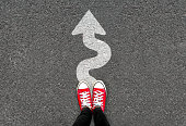 Feet and white arrow sign go straight on road background. Top view of woman. Forward movement and motivation idea concept.