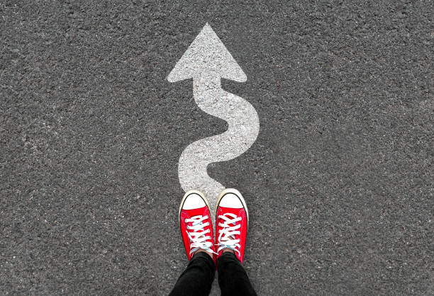 Feet and white arrow sign go straight on road background. Top view of woman. Forward movement and motivation idea concept. Feet and white arrow sign go straight on road background. Top view of woman. Forward movement and motivation idea concept. Selfie of foot and legs in red sneaker shoes on pavement floor from above. running shoes on floor stock pictures, royalty-free photos & images