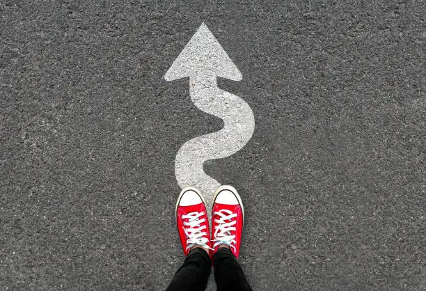 Photo of Feet and white arrow sign go straight on road background. Top view of woman. Forward movement and motivation idea concept.