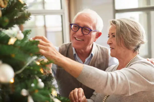 Photo of Senior couple decorating the Christmas tree.