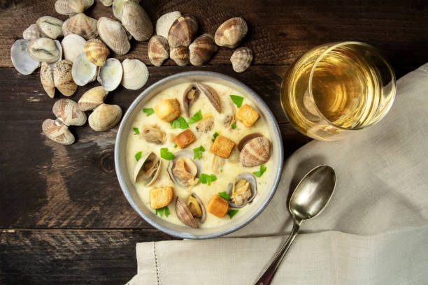 clam chowder with fresh parsley and croutons, with shells and a glass of white wine, shot from above on a dark rustic wooden background with copyspace - surf and turf fotos imagens e fotografias de stock