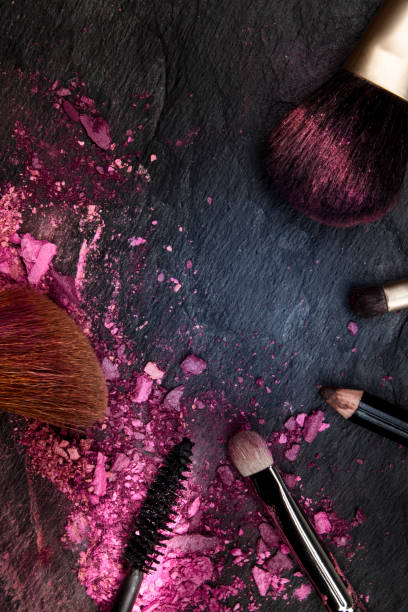 istock Make-up brushes with broken cosmetics, shot from the top on a dark background forming a frame with a place for text, a beauty design template for a makeup banner 1180147168