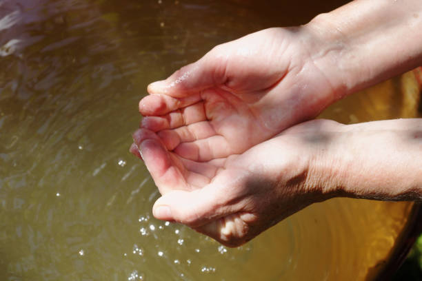 istock An old woman scoops clean water from a barrel with her hands 1180147933