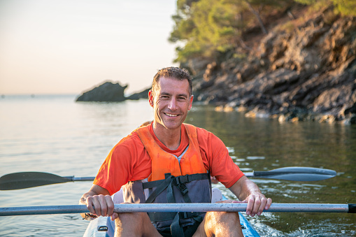 Close-up of smiling male Caucasian kayaker in mid 40s returning to shore from paddling in Mediterranean off coast of Spain.