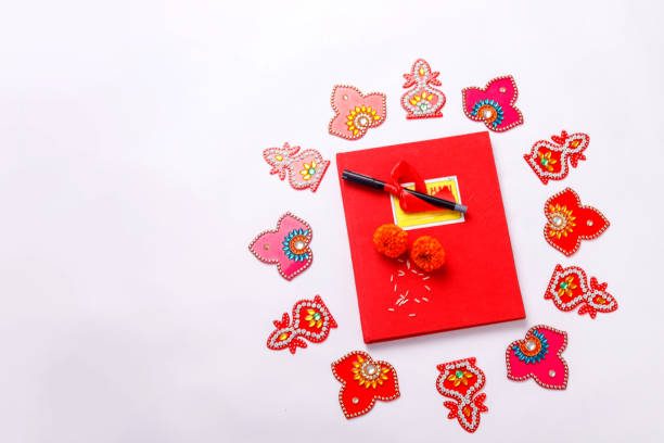 istock Red accounting note book , diya, and flower rangoli on white background 1180151695