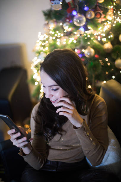 istock Happy young woman calling mobile in front of Christmas tree 1180155647