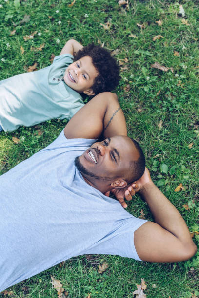 istock happy african american father and son lying on lawn while resting in park 1180156542
