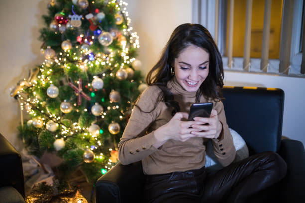 istock Happy young woman calling mobile in front of Christmas tree 1180157855