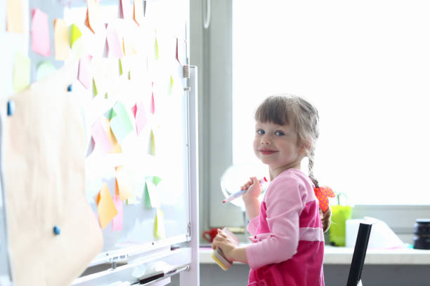 istock Little child hold red marker against whiteboard 1180158408