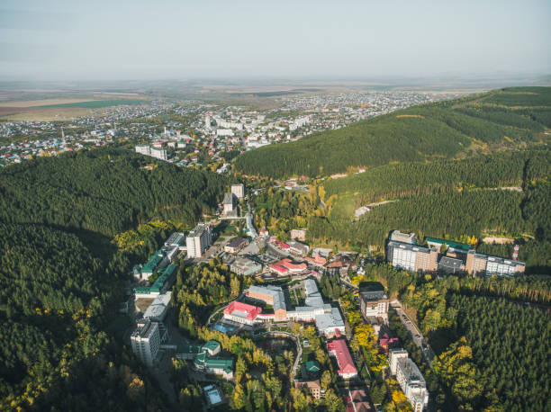 vista aérea de uma cidade pequena no território de altai. vista superior da cidade do recurso belokurikha. vista do pássaro-olho das casas entre as florestas nas inclinações das montanhas. - recreate - fotografias e filmes do acervo