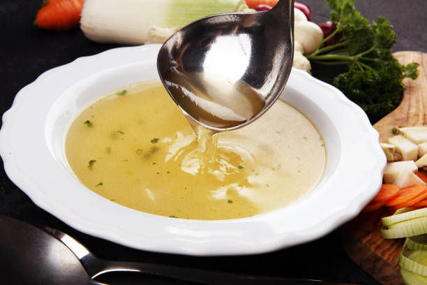 istock Broth with carrots, onions various fresh vegetables in a pot - colorful fresh clear spring soup. Rural kitchen scenery vegetarian broth 1180160521