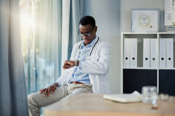 Almost time for my consultation with the next patient Shot of a young doctor checking the time on his watch in his office its almost time stock pictures, royalty-free photos & images