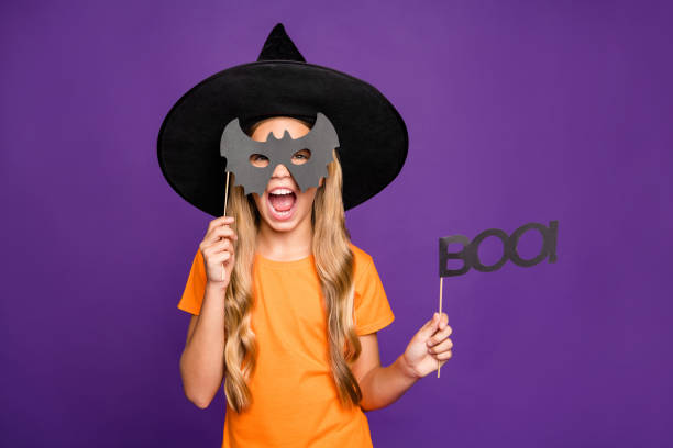 grr! foto di piccola signora strega giocare ruolo paranormale halloween tema party tenendo bastone di carta pipistrello aspetto spaventoso indossare arancione t-shirt wizard cappello isolato sfondo di colore viola - witch smiling evil bizarre foto e immagini stock