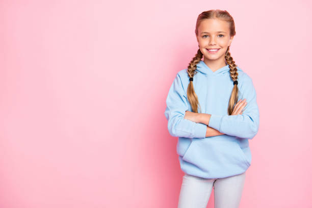 foto de alegre positivo tipo amigable chica linda de pie con confianza con los brazos cruzados cerca del espacio vacío para ser cumplido con anuncios aislados sobre el fondo de color pastel - little girls small blond hair child fotografías e imágenes de stock