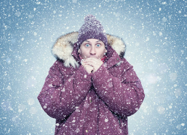 Frozen man in red winter clothes warms his hands, cold, snow, frost, blizzard Frozen man in red winter clothes warms his hands, cold, snow, frost, blizzard warms stock pictures, royalty-free photos & images