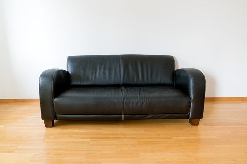 A horizontal view of a dark brown leather couch in a minimalist apartment