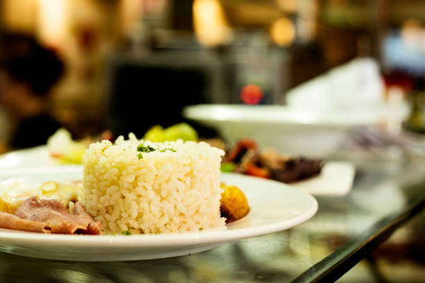 some plates in an open kitchen of a restaurant ready to be served, one of them, in the foreground a combo platter consisting of cooked rice, fried eggs, some potato chips and some slices of sirloin