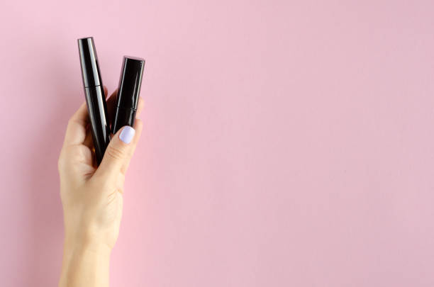 istock Hand with black mascara composition on pink background. 1180170883