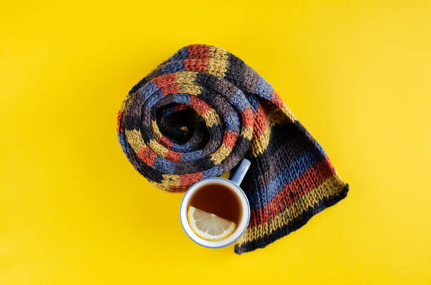 istock Woolen scarf with tea cup and lemon slice composition on yellow background. 1180172448