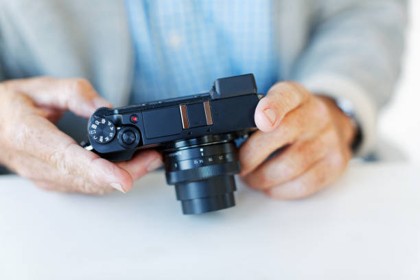 Male hands hold an unbranded camera A man's hands adjust something on a point-and-push camera he holds. point and shoot camera stock pictures, royalty-free photos & images