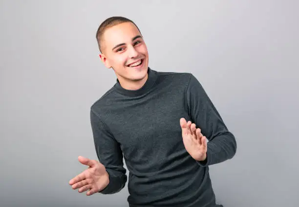 Photo of Happy smiling young man clapping one's hands on blue background. Closeup