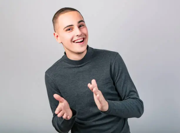 Photo of Happy smiling young man clapping one's hands on blue background. Closeup