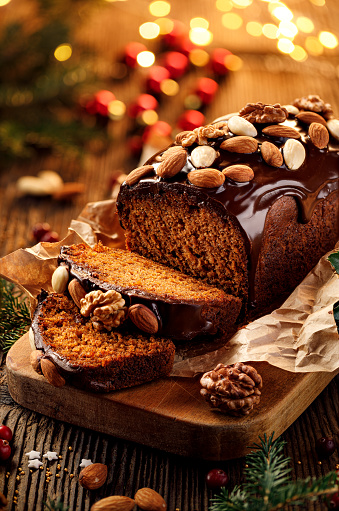 Christmas gingerbread cake covered with chocolate and decorated with nuts and almonds on the holiday table, close-up. Christmas dessert