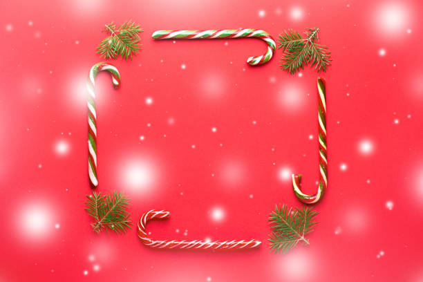 rectangular frame from candy canes and fir tree on red background with snow. minimalistic christmas or new year concept flat lay, copy space - hard candy candy pink wrapping paper imagens e fotografias de stock