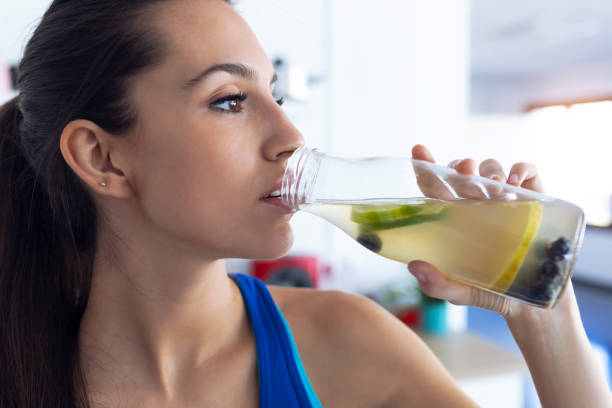 beautiful sporty young woman drinking detox juice in the kitchen at home