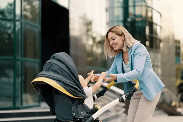 Portrait of a successful business woman in blue suit with baby. Business woman pushing baby stroller