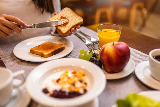istock Young woman spreading jam on a toast 1180180269