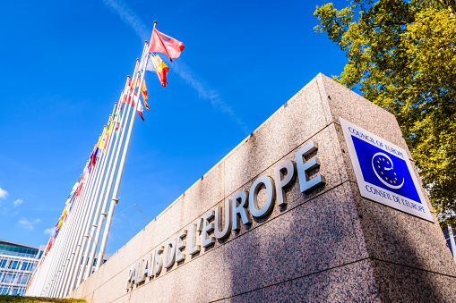 Strasbourg, France - September 13, 2019: Low angle view of the sign of the palace of Europe, which houses the seat of the Council of Europe, and a row of flagpoles with european countries flags.