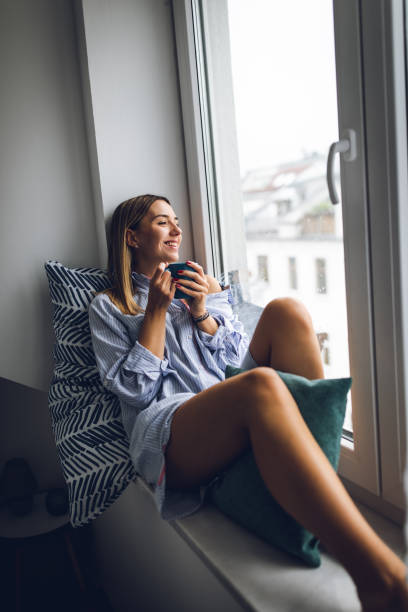 istock Young woman relaxing on window sill 1180180701