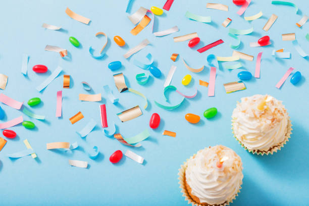 istock birthday hat with confetti and cupcake on blue paper background 1180182774