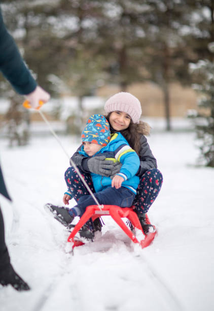 istock Brother and sister sledding in winter. 1180186228