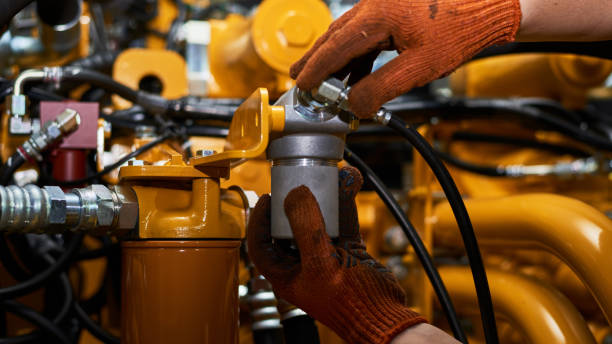 Low key photo of hydraulic pipes maintenance on heavy industry machine. Low key photo of hydraulic pipes maintenance on heavy industry machine in a garage. hydraulic hose stock pictures, royalty-free photos & images