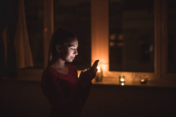 Beautiful woman using phone in dark room