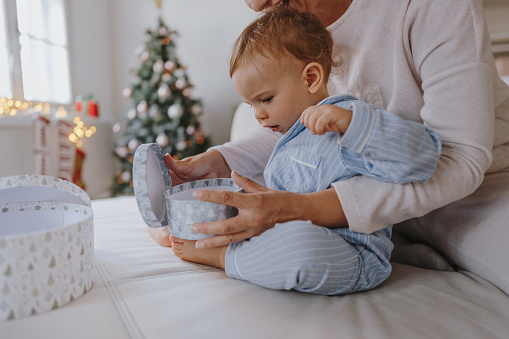 Photo of mother and baby boy at home on Christmas morning, opening presents together