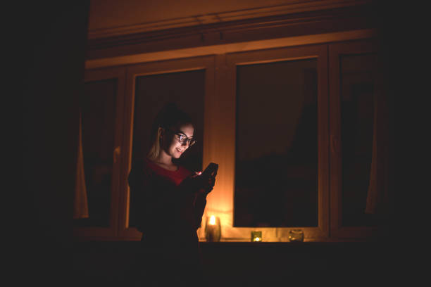 istock Beautiful woman using phone in dark room 1180190168