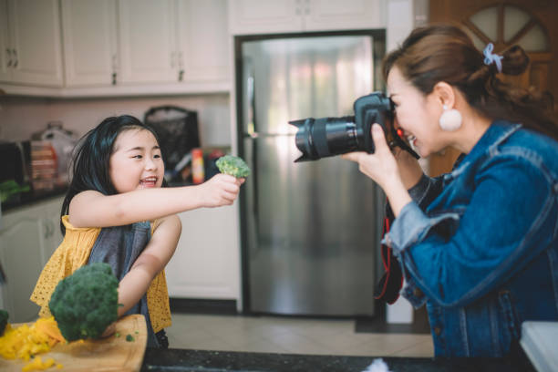 una madre china asiática tomando fotografía de su hija preparando comida en la cocina - cámara digital fotos fotografías e imágenes de stock