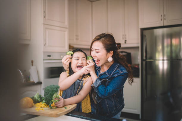 台所で食べ物を準備する彼女の娘との絆の時間を持つアジアの中国人の主婦 - 中国人 ストックフォトと画像