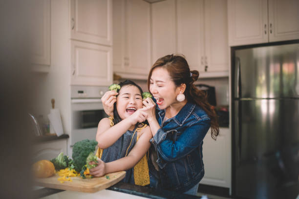An Asian Chinese housewife having bonding time with her daughter in kitchen preparing food An Asian Chinese housewife having bonding time with her daughter in kitchen preparing food broccoli photos stock pictures, royalty-free photos & images