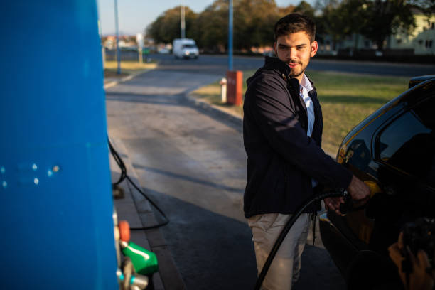 istock Handsome young man refueling the car in a sunny day 1180191349