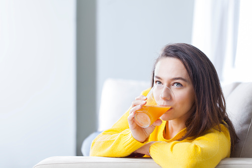 Young woman drinking orange juice at home