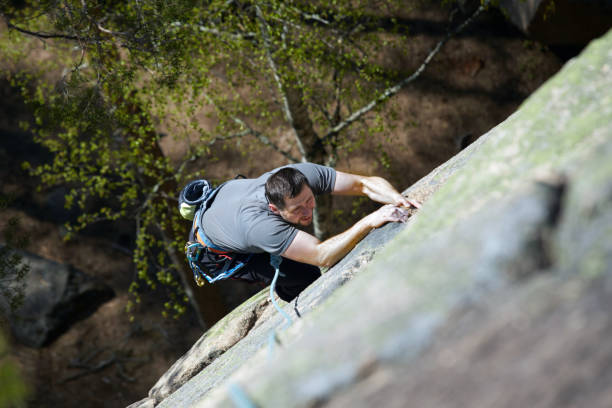 女性のロッククライマーは岩の壁に登る。上からの眺め - climbing wall rock climbing holding reaching ストックフォトと画像