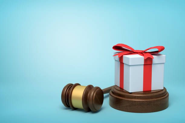 3d rendering of white gift box with red ribbon on round wooden block and brown wooden gavel on blue background stock photo